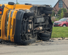Staffer, other driver injured after crash causes school bus to roll 